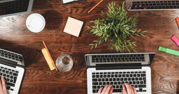 people working together around a table with laptops, coffee and notebooks