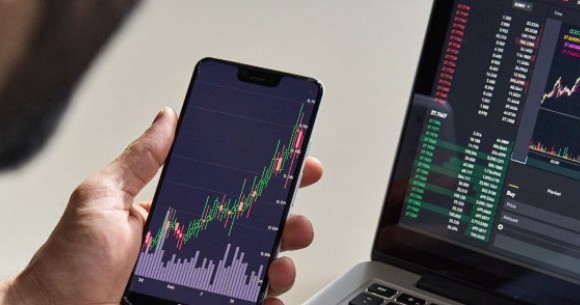 Person sat at desk with laptop and devices showing various charts and analytics